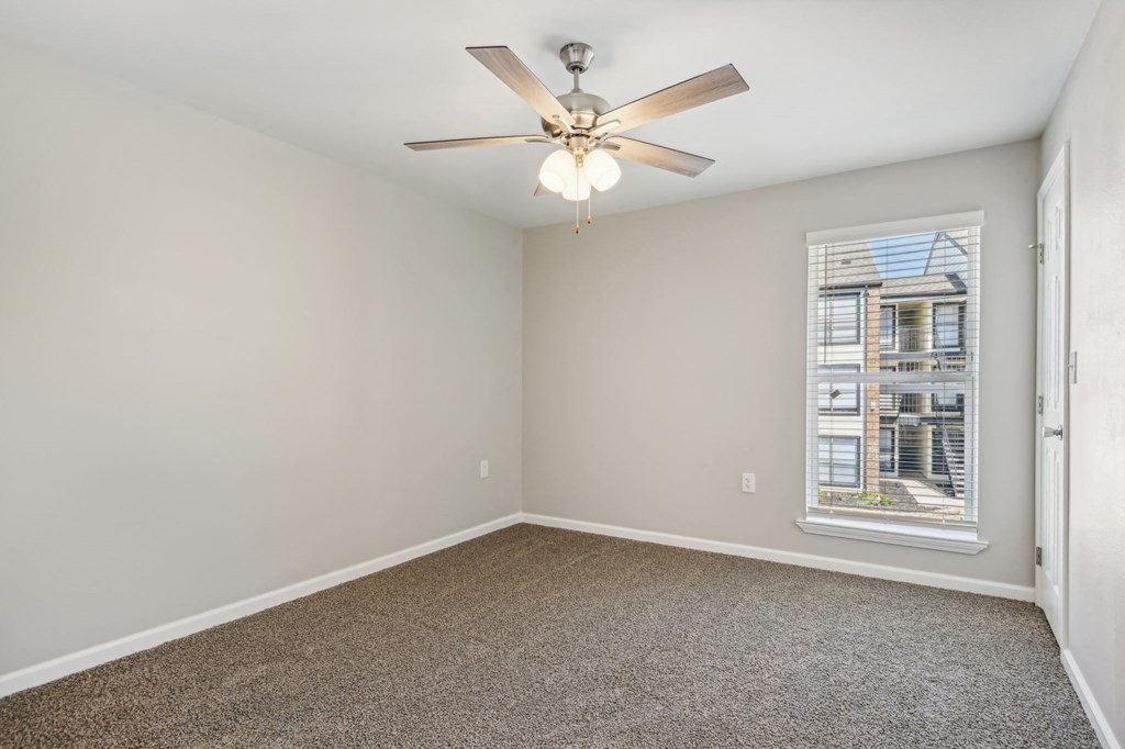 an empty living room with a ceiling fan and a window at The Glen at Highpoint, Dallas, 75243