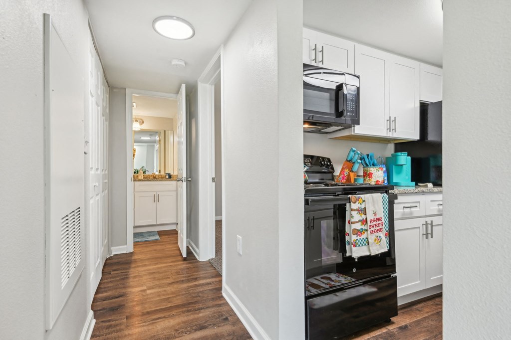 a renovated kitchen with white cabinets and a black stove and microwave at The Glen at Highpoint, Dallas, 75243
