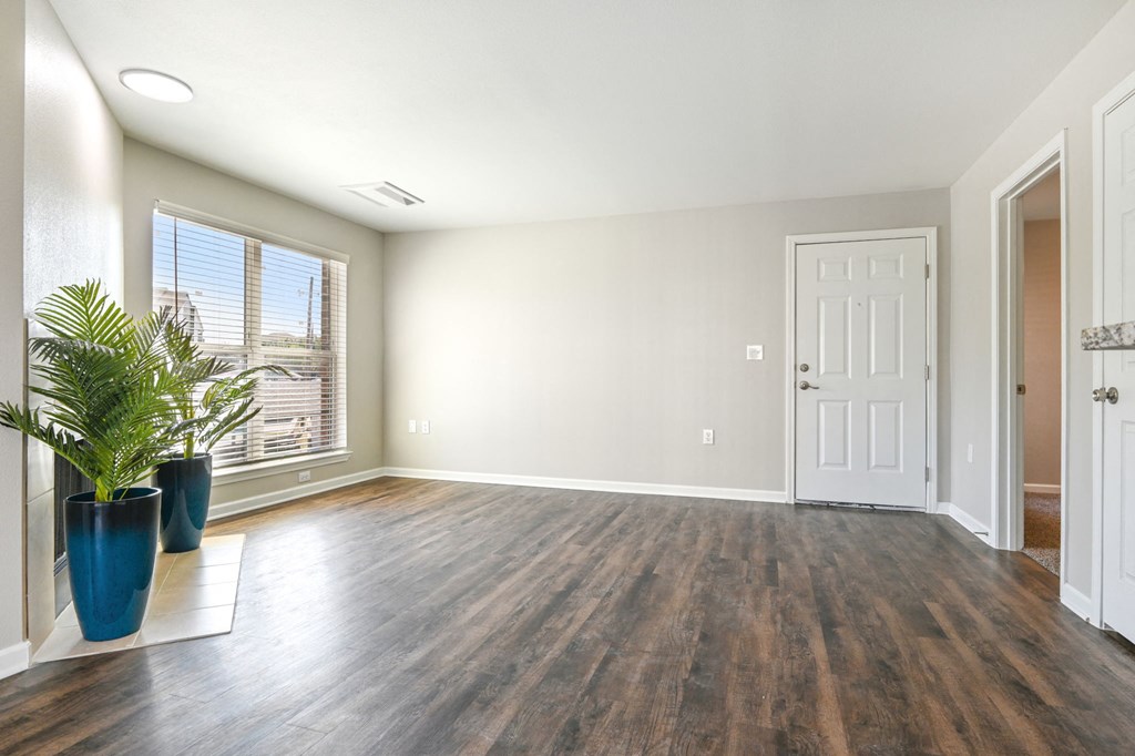 an empty living room with a white door and a potted plant at The Glen at Highpoint, Dallas, 75243