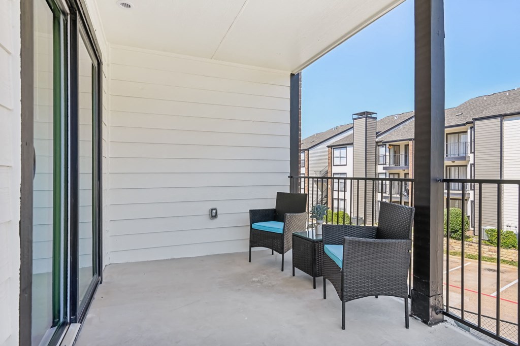 a patio with chairs and a table and a sliding glass door at The Glen at Highpoint, Dallas, 75243