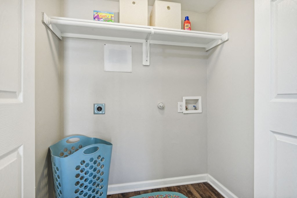 a small laundry room with a blue laundry basket and a shelf at The Glen at Highpoint, Dallas, 75243
