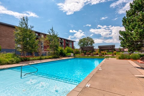 A swimming pool surrounded by a concrete walkway and a building in the background.