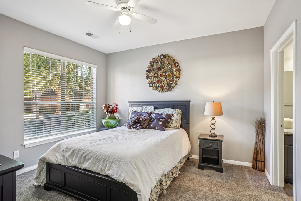 A bedroom with a bed, nightstand, and window.