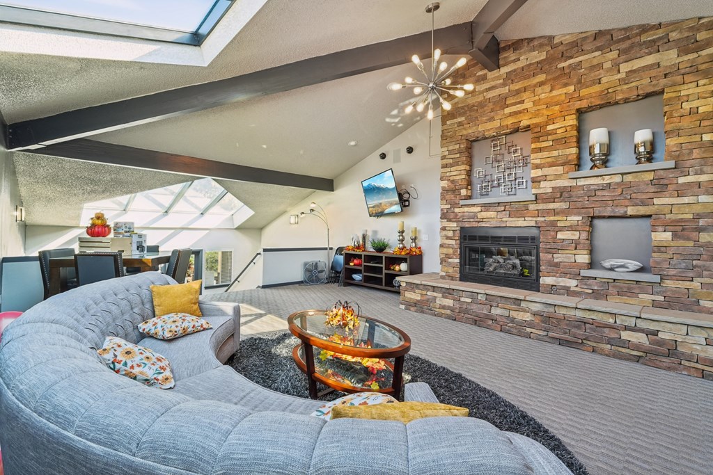 A living room with a grey couch and a stone fireplace.