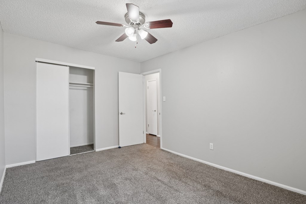 A room with a ceiling fan and carpeted floor.at Aspen Townhomes, Colorado Springs, Colorado