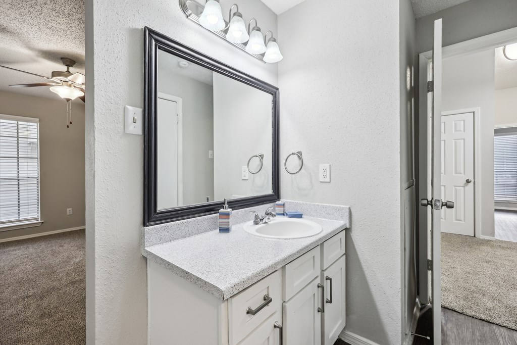 A bathroom with a sink, mirror, and a ceiling fan at The Willows on Rosemeade, Dallas, TX 75287