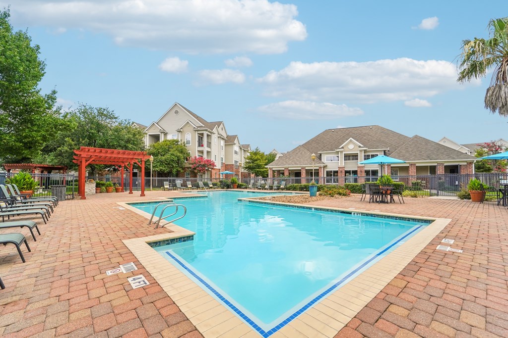 A swimming pool surrounded by a brick patio and lounge chairs.at Kingwood Glen, Kingwood, 77339