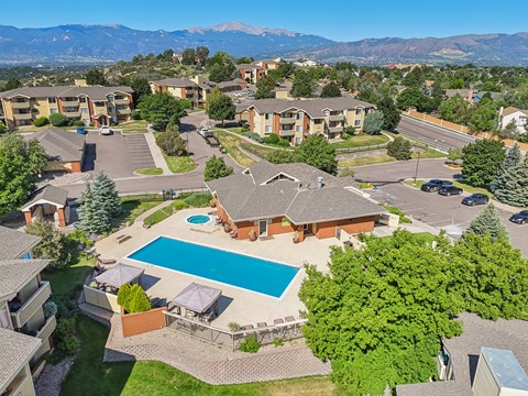 A large apartment complex with a swimming pool and a view of mountains in the background.