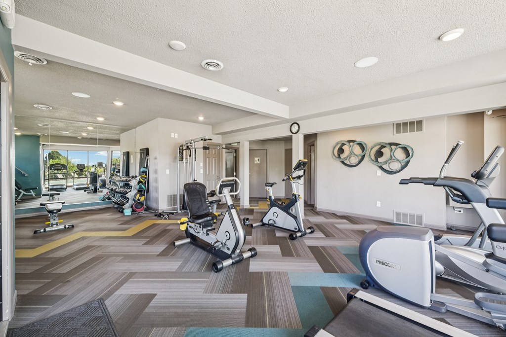 A gym with exercise equipment and a mirror on the wall.