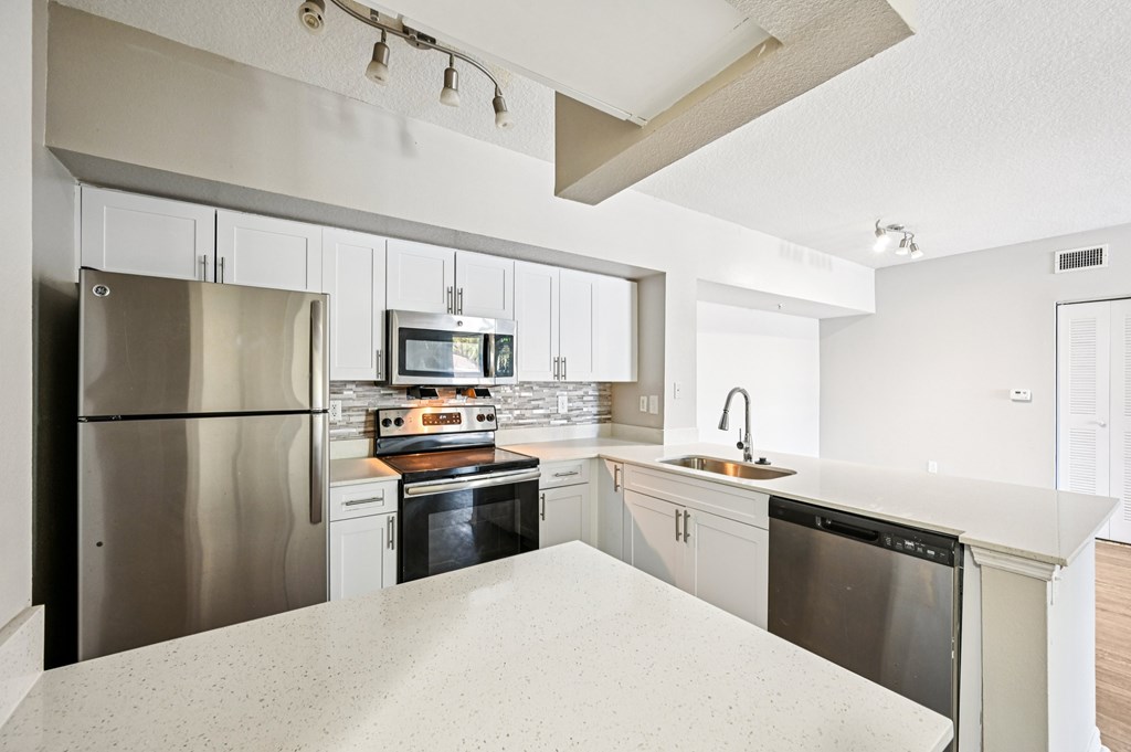 A modern kitchen with stainless steel appliances and white countertops. at Heritage Bay, Jensen Beach, Florida