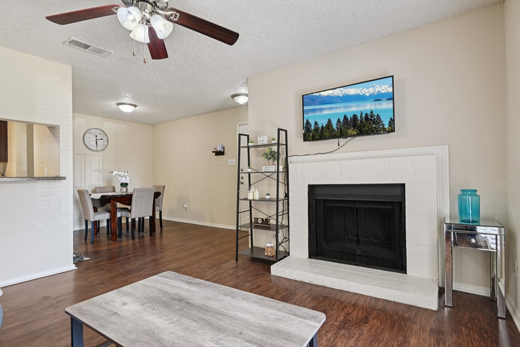 A living room with a fireplace and a television mounted above it. at The Glen, Lewisville, TX