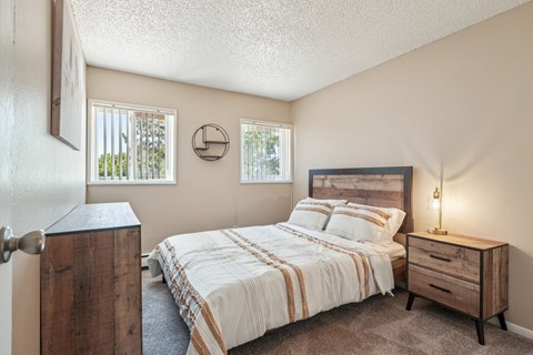 A bedroom with a bed, nightstand, and window.