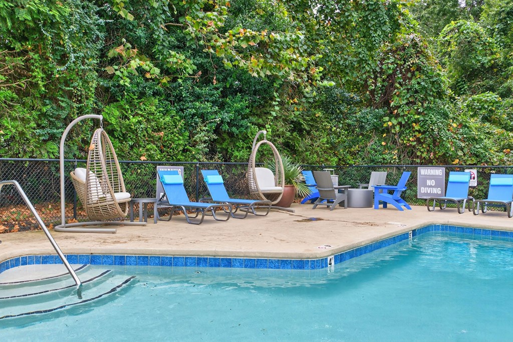 A pool surrounded by trees and chairs.at Lofts of Wilmington, Wilmington, North Carolina
