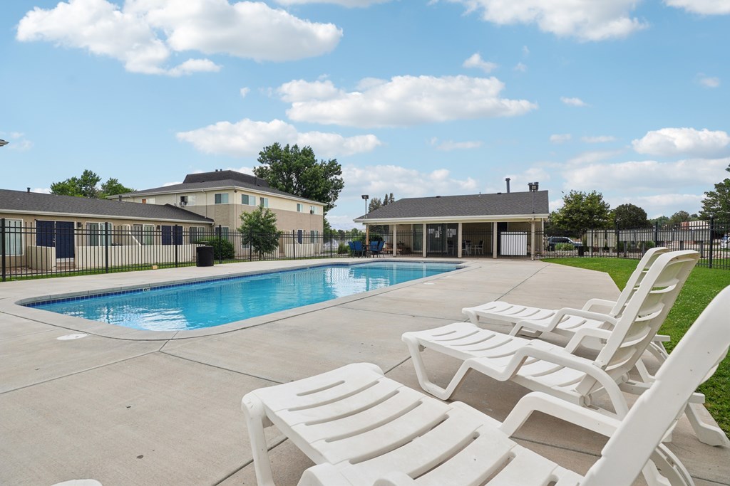 A pool surrounded by white lounge chairs.at Aspen Townhomes, Colorado Springs, 80909