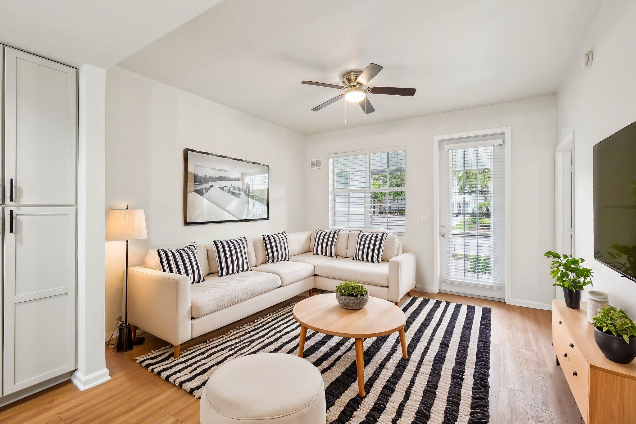 A living room with a striped couch and a ceiling fan.