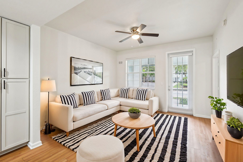 A living room with a striped couch and a ceiling fan.