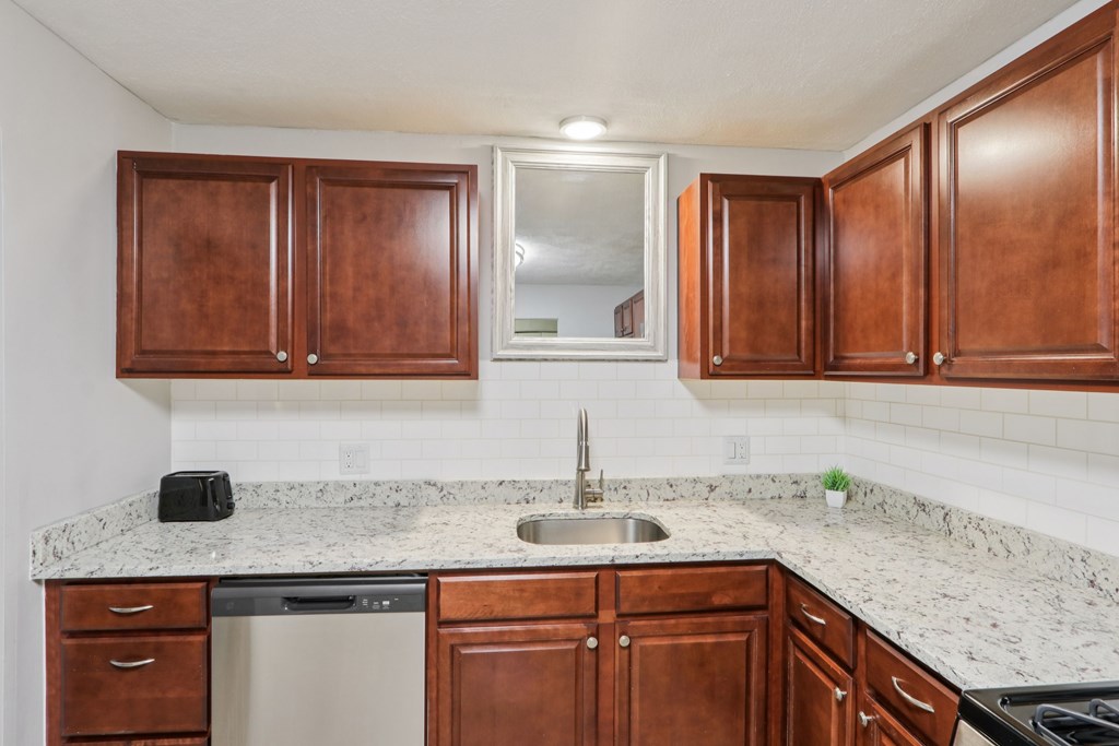 A kitchen with brown cabinets and granite countertops. at Heritage at the River, Manchester, New Hampshire