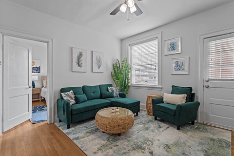 A living room with a green couch and a wicker coffee table.
