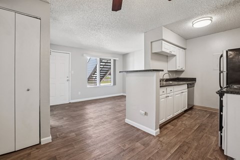 A kitchen with white cabinets and a wooden floor.