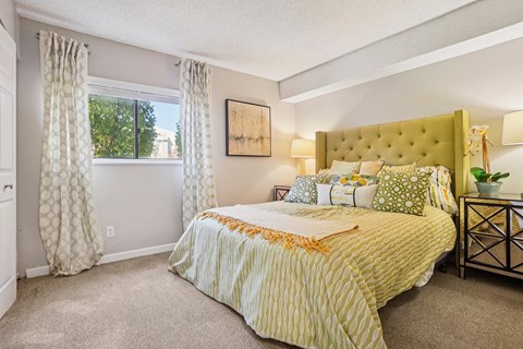 A bedroom with a large bed and a window with curtains. at Deer Crest Apartments, Broomfield, Colorado
