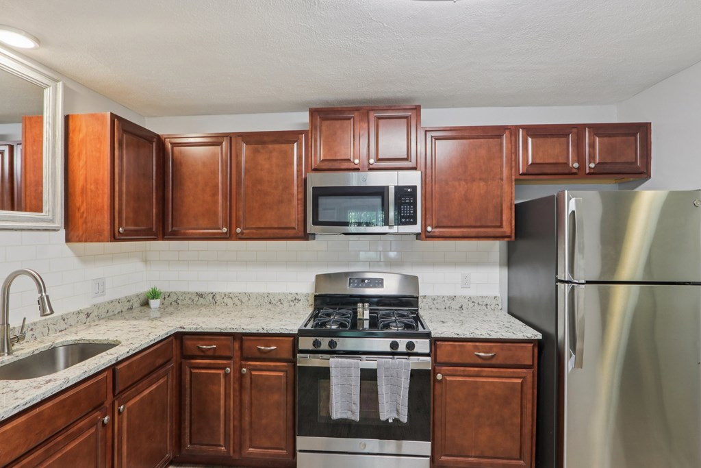 A kitchen with a stove top oven and a refrigerator. at Heritage at the River, Manchester, NH
