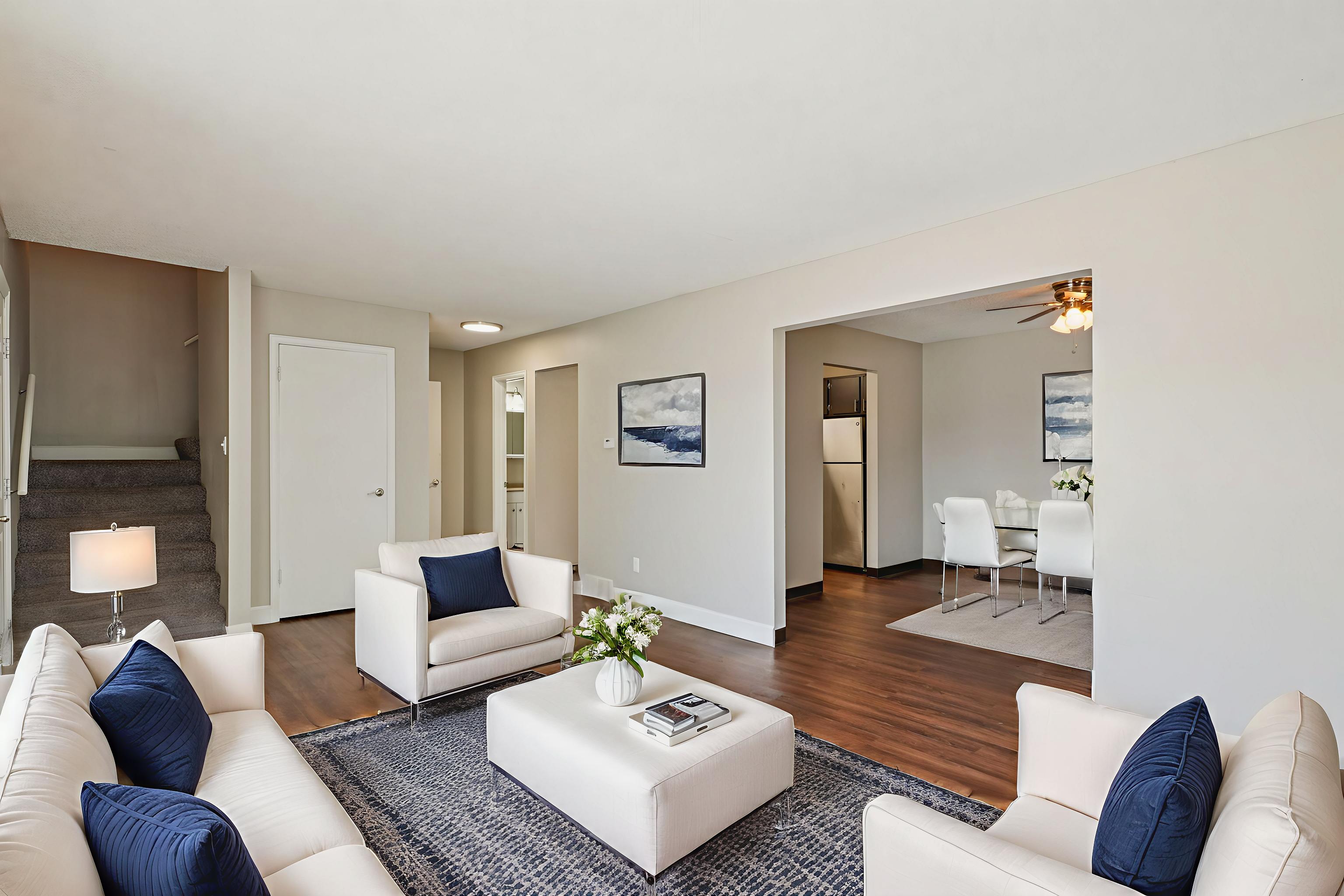 A living room with white furniture and a rug.