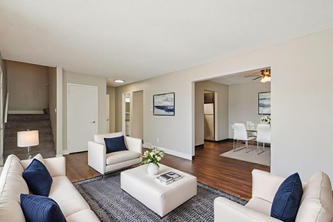 A living room with white furniture and a rug.