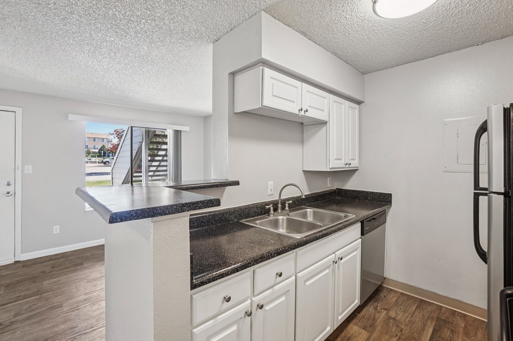 A kitchen with white cabinets and a black countertop.