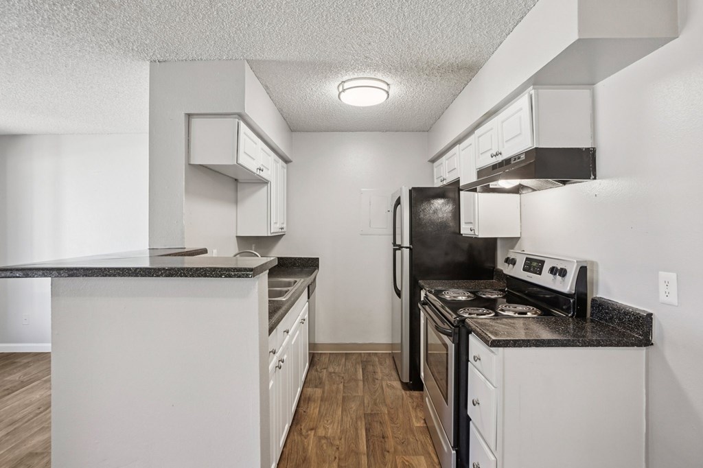 A kitchen with white cabinets and a black countertop.