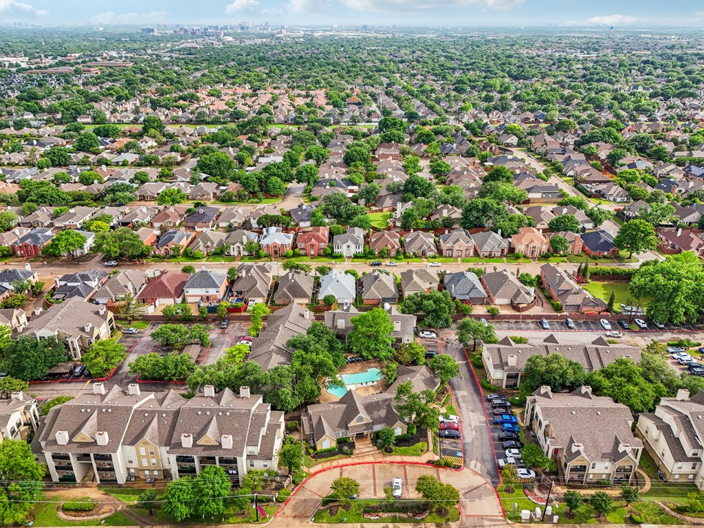 A bird's eye view of a suburban neighborhood with houses and a pool at The Willows on Rosemeade, Dallas, TX 75287