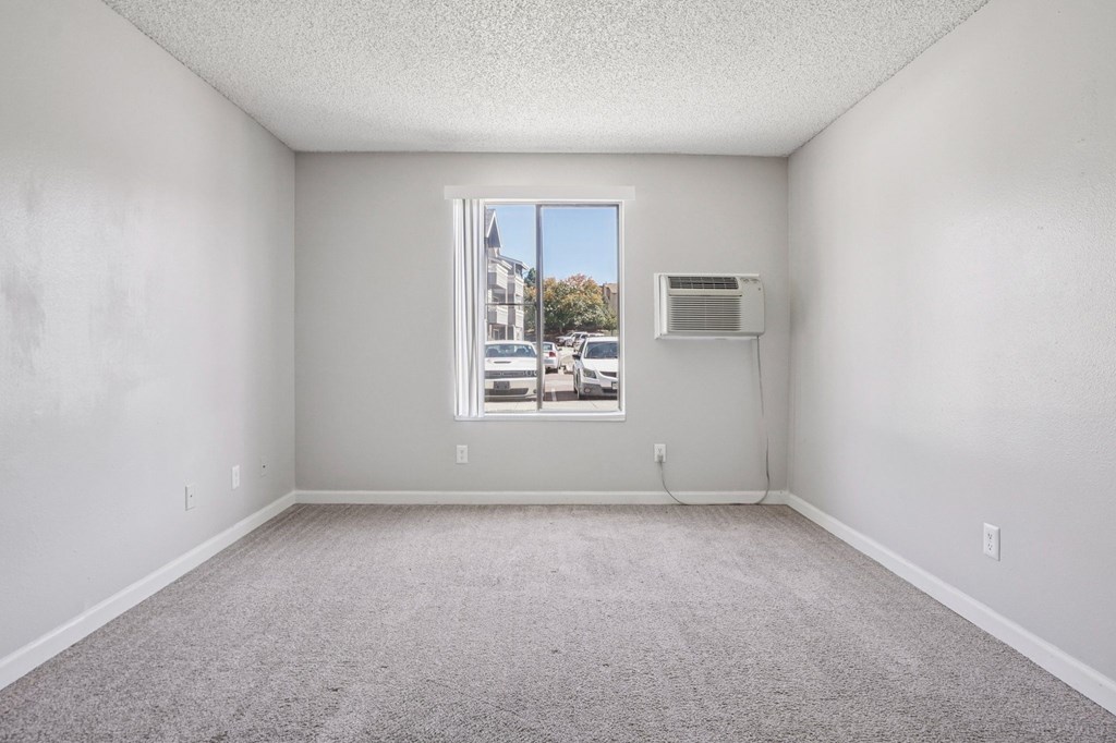 A room with a window and a wall-mounted air conditioner unit.