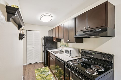A modern kitchen with a black stove top oven and a white microwave.