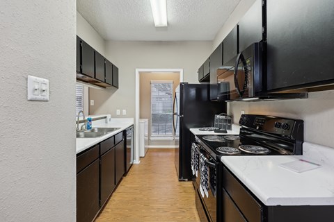A kitchen with black cabinets and white countertops.