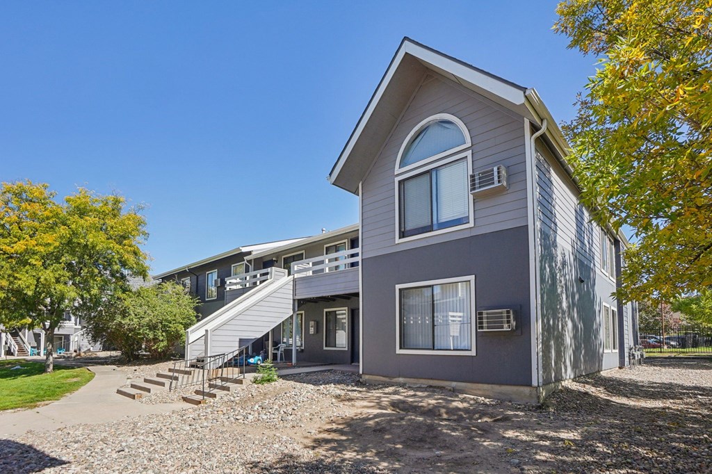 A grey house with a white balcony and a small porch.