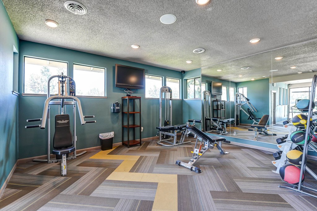 Gym with weights and cardio machines and a tv  at Union Heights Apartments, Colorado Springs, CO