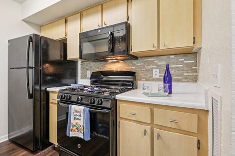 A kitchen with a black refrigerator and stove top oven.