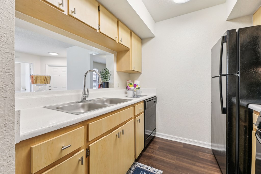 A kitchen with wooden cabinets and a black refrigerator. at University Park Apartments, Orlando, Florida