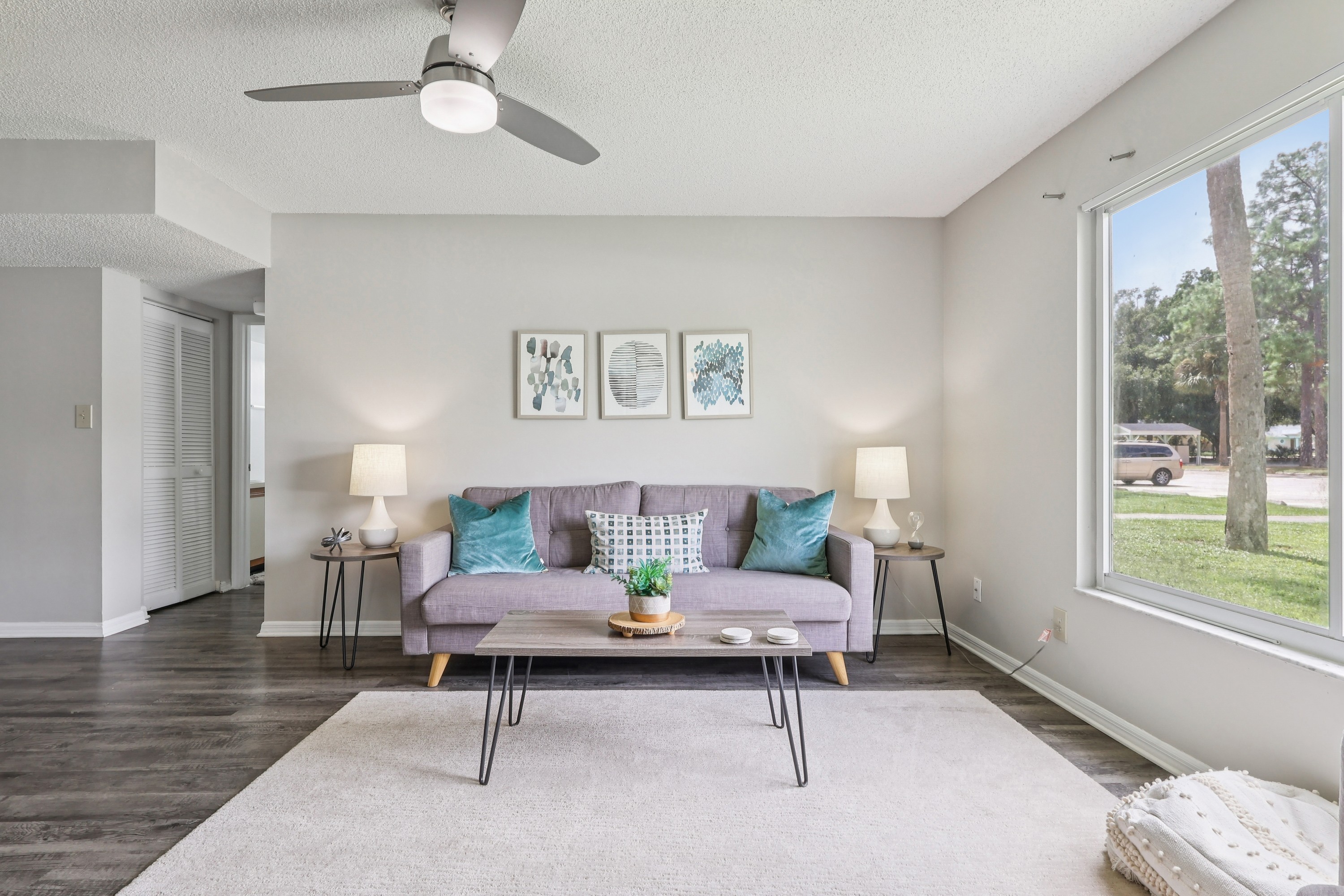 A living room with a grey couch and a grey rug.