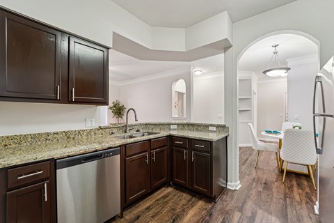 A kitchen with dark brown cabinets and granite countertops.