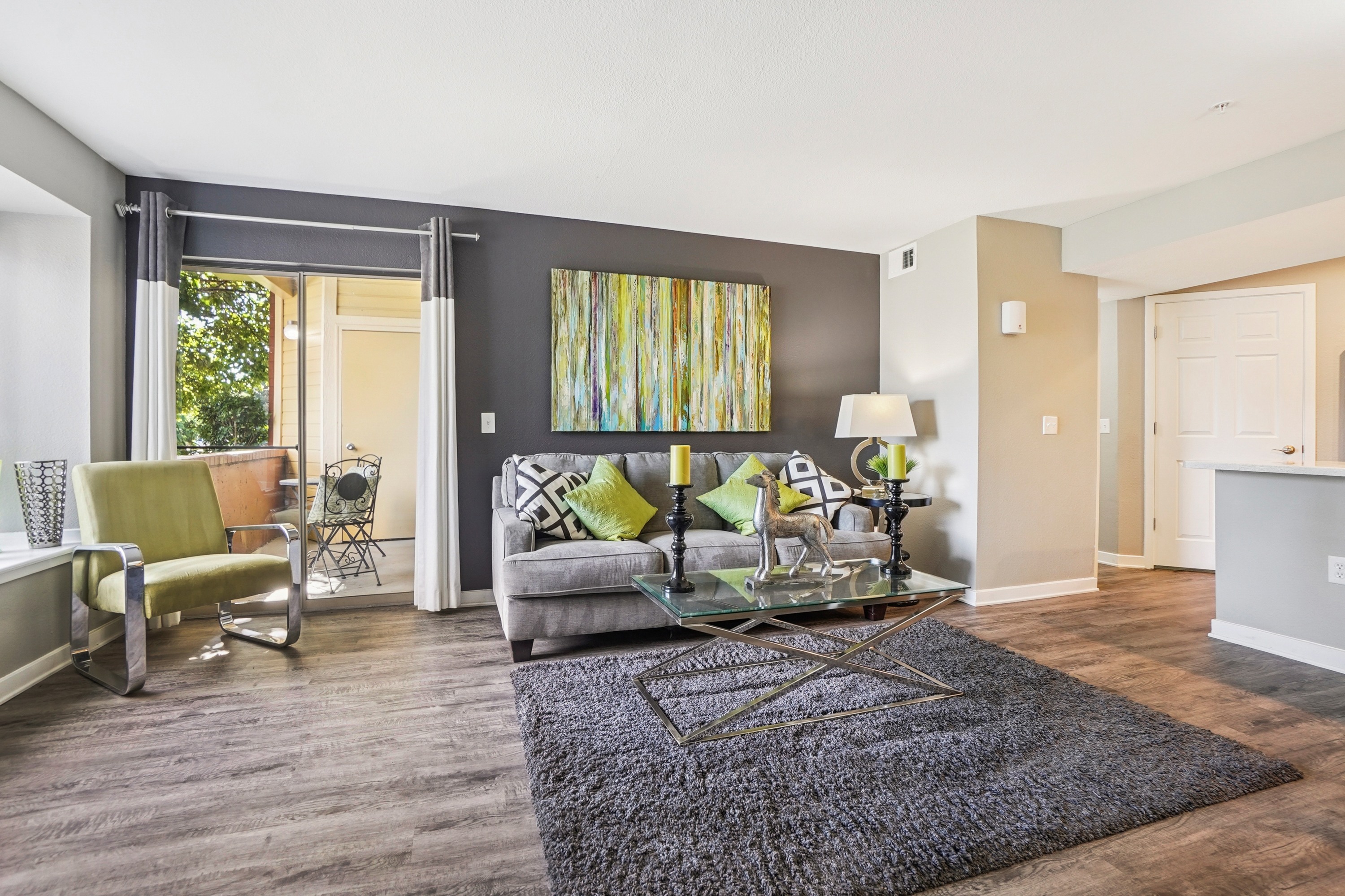 A living room with a grey couch and a glass coffee table.