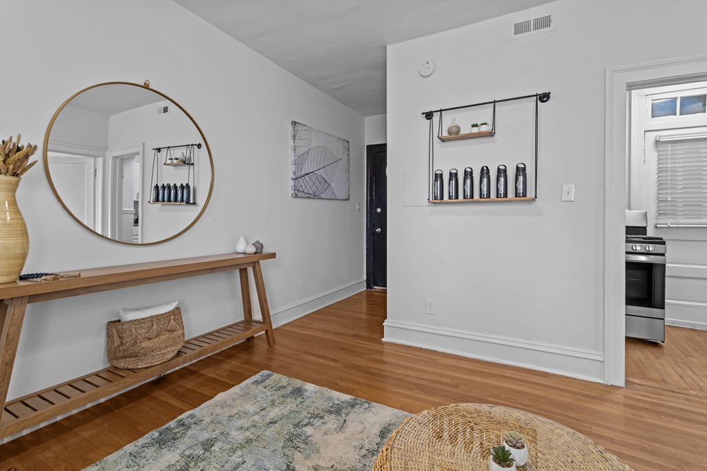 A kitchen with a wooden floor and a round mirror on the wall.