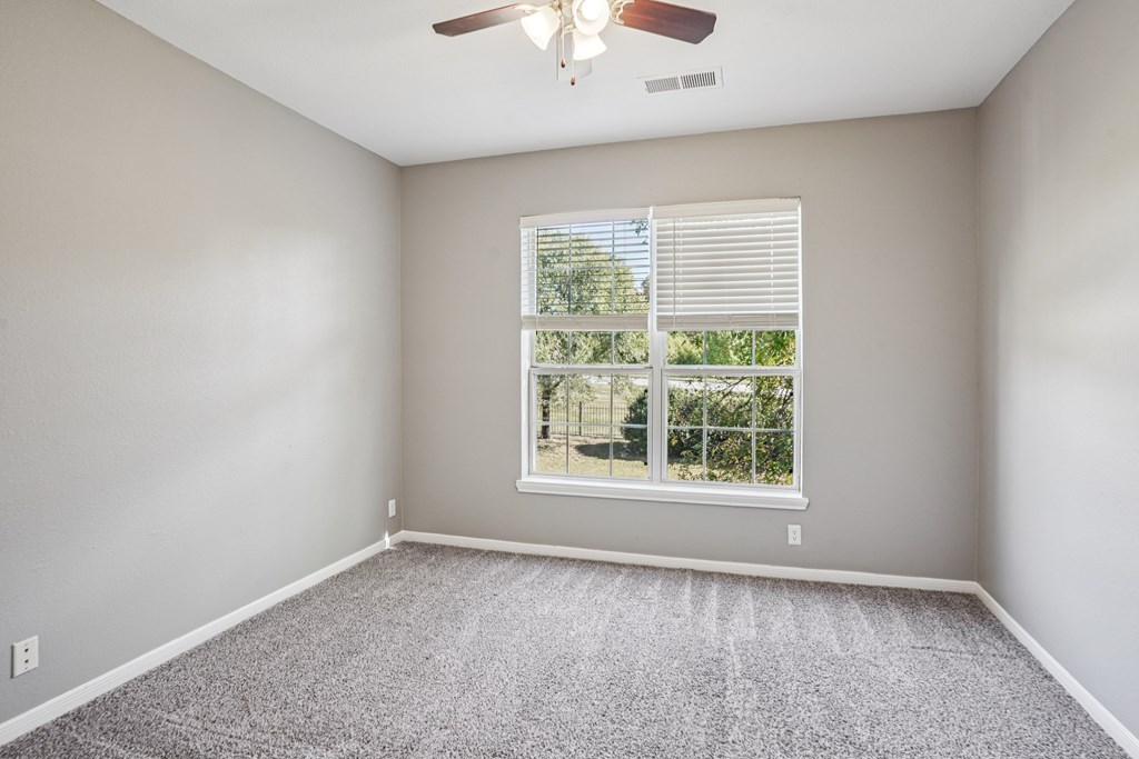 A room with a ceiling fan and a window with blinds.