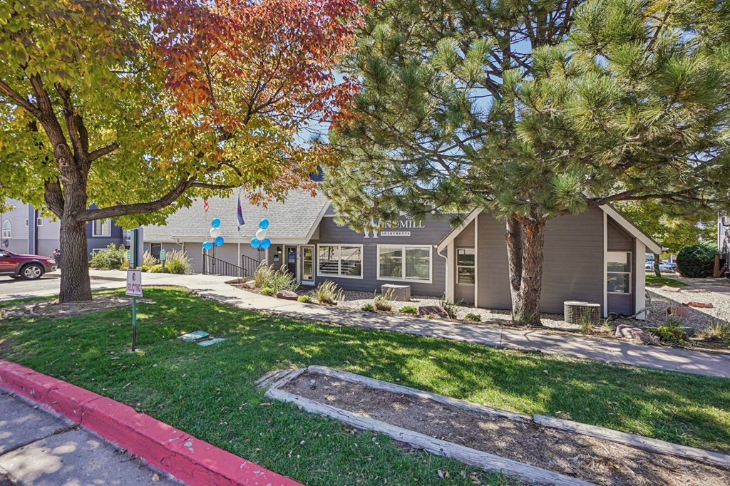 A tree with red leaves is in front of a house.