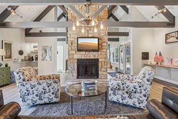 A living room with a stone fireplace and a chandelier.