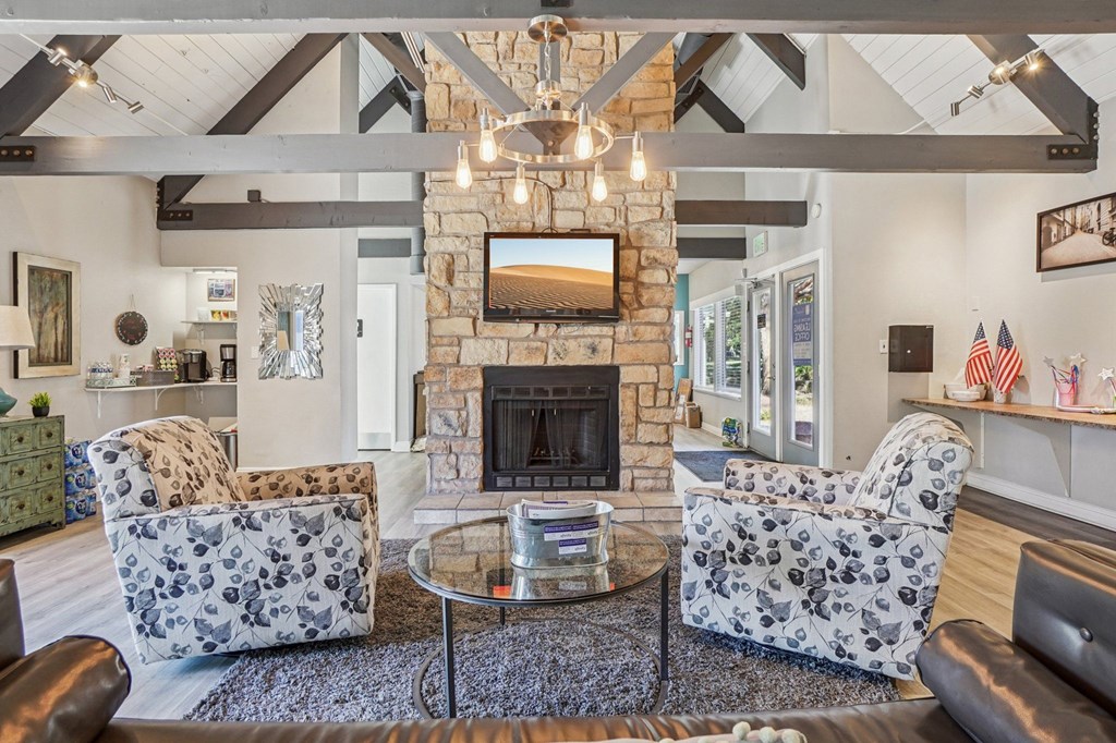 A living room with a stone fireplace and a chandelier.