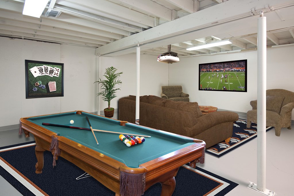 A pool table in a room with a TV showing a football game.