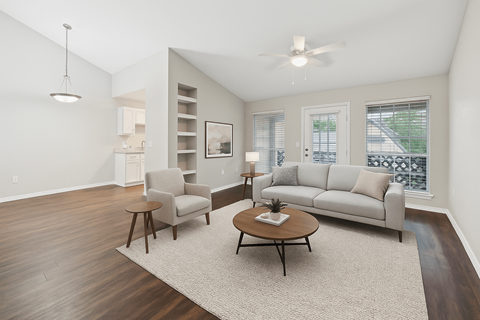 A living room with a grey couch, a chair, a coffee table, and a ceiling fan.