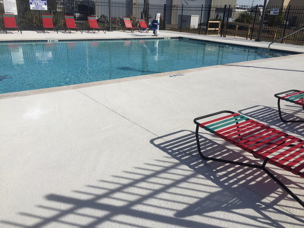 Swimming pool with a red chairs next to it at River Crossing Apartments, Thunderbolt, GA, 31404