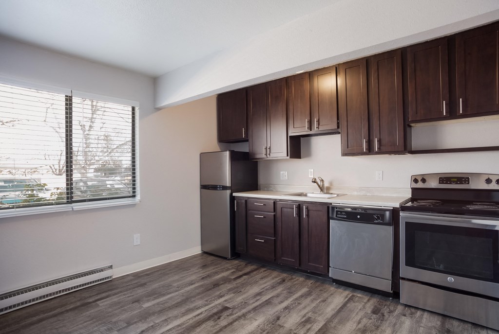 Empty kitchen with wooden cabinets and stainless steel appliances and a window  at Governor's Park, Fort Collins, 80525