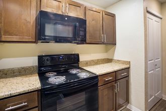 Kitchen with brown cabinets and black appliances at Arcadia Townhomes, Federal Way, WA